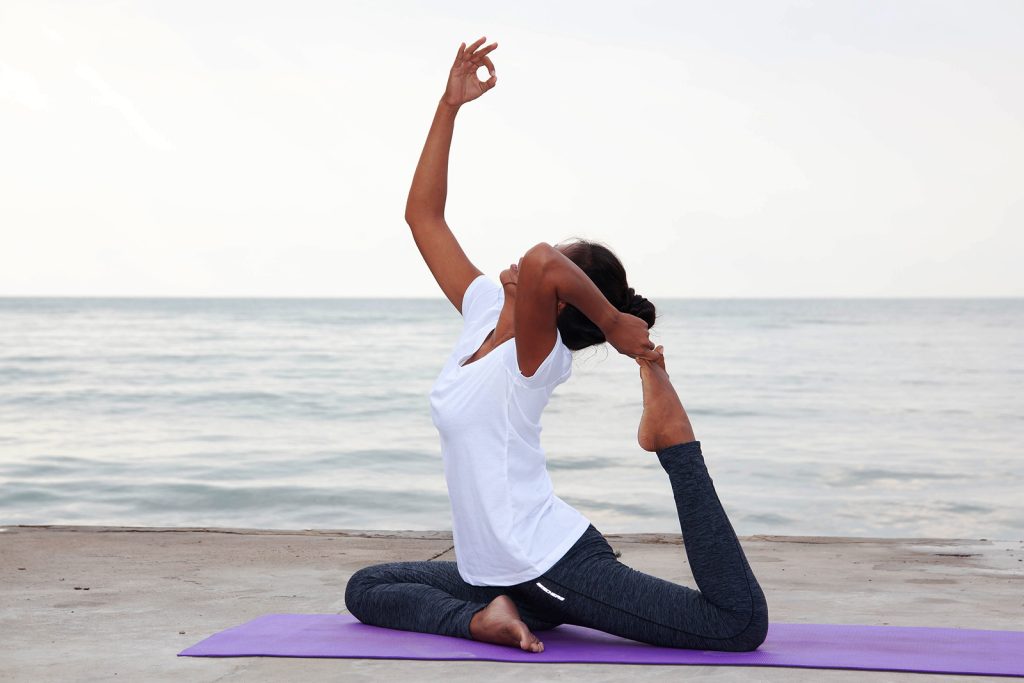 Yoga session on the beach in Pranburi, Thailand, at Taotherapy Rehab, with participants practicing yoga near the ocean under a peaceful sky.