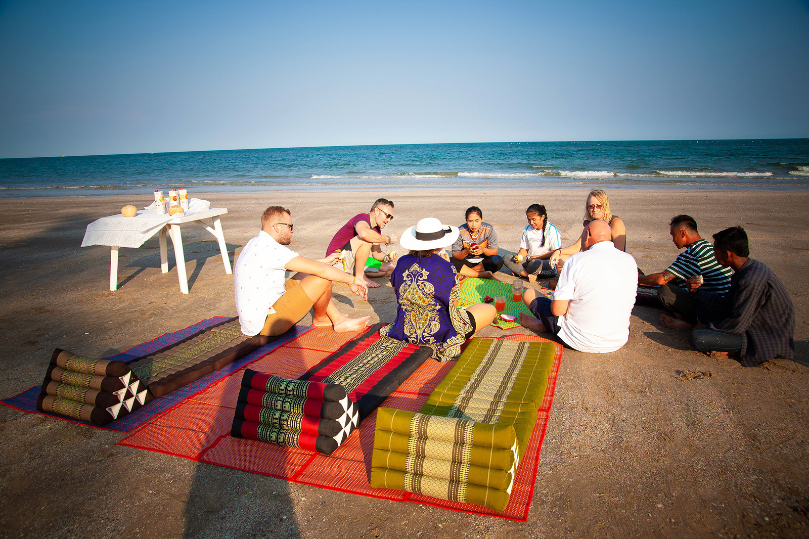 A group discussion taking place on the beach in Pranburi, Thailand, at Taotherapy Rehab, with participants sitting in a circle near the shoreline